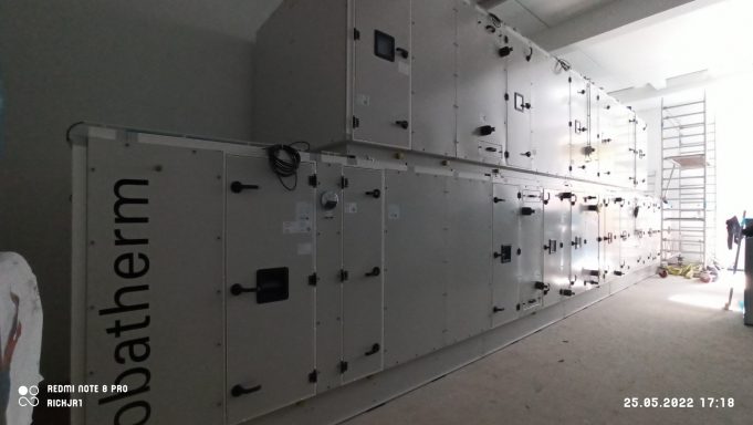 Große, helle Klimaanlage mit mehreren seitlichen Lüftungselementen in einem Raum.